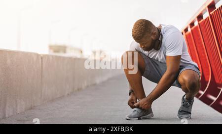 Afro Kerl die Kontrolle über seine Schnürsenkel auf Brücke Stockfoto