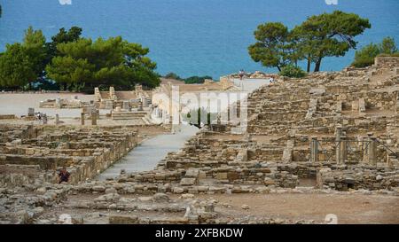 Antike Ruinen mit Meerblick, umgeben von Vegetation und verstreuten Besuchern, hellenistische Häuser, Kamiros, archäologische Stätte, antike Stadt Stockfoto