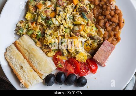 Rührei-Frühstück mit grünen, orangen und gelben Paprika, Pilzen, gebackenen braunen Bohnen, roten Tomatenscheiben, schwarzen Oliven, Country-STYLE Stockfoto