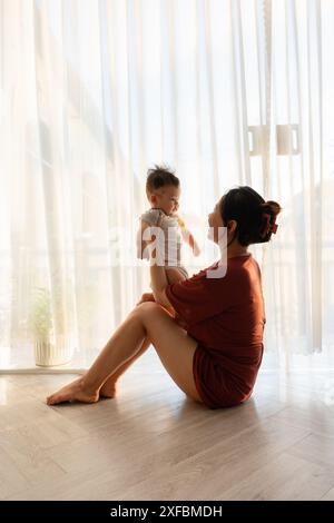 Eine Frau, die auf dem Boden sitzt und ein Baby hält Stockfoto