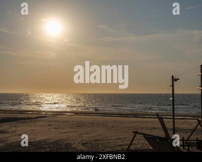 Sonnenuntergang über einem ruhigen Meer und einsamen Strand schafft eine stimmungsvolle und beruhigende Atmosphäre, de Haan, Flandern, Belgien, Europa Stockfoto
