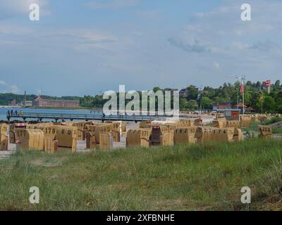 Nummerierte Liegestühle Reihen sich entlang eines Sandstrandes mit Wasser und bläulichem Himmel im Hintergrund, Eckernförde, schlewsiwg-holstein, deutschland Stockfoto