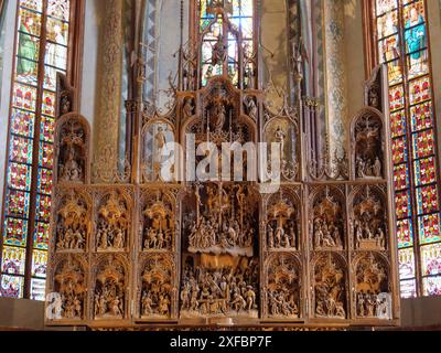 Kunstvoller Holzaltar in einer Kirche vor bunten Buntglasfenstern, Stein, schleswig. deutschland Stockfoto