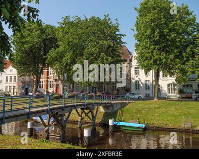 Kanal mit Holzbogenbrücke, umgeben von hohen Bäumen und historischen Gebäuden im Hintergrund, friedrichstadt, schleswig-holstein, deutschland Stockfoto