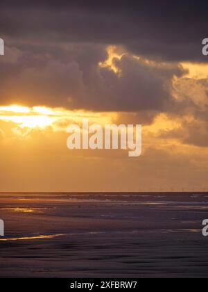 Sonnenuntergang über dem Meer mit einem bewölkten Himmel und einem schimmernden orange Licht, saftig, Nordsee, deutschland Stockfoto