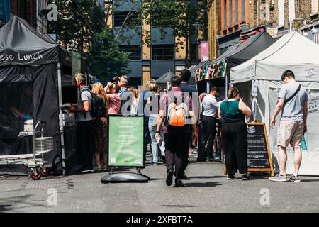 London, Großbritannien - 27. Juni 2024: Ein Street Food Market in London ist voller Menschen. Die Leute warten in der Schlange an verschiedenen Imbissständen, um den Taucher auszuprobieren Stockfoto