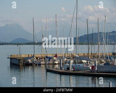 Ein ruhiger Hafen mit verankerten Segelbooten und Bergen im Hintergrund an einem klaren Tag, lindau, bayern, deutschland Stockfoto