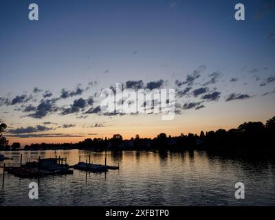 Der Abendhimmel spiegelt sich im ruhigen See, während die Boote an einem Steg in lindau, bayern, deutschland, ankern Stockfoto