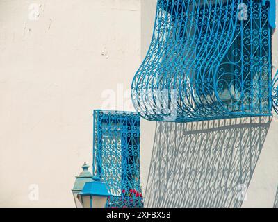 Blau lackierte schmiedeeiserne Fenstergitter an einer hellen Wand, Schatten werfen, Tunis, Tunesien Stockfoto