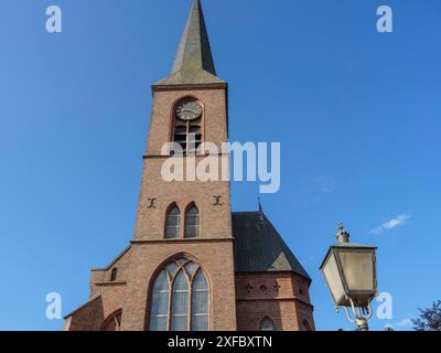 Nahaufnahme eines hohen gotischen Backsteinkirchturms mit Uhr, vor blauem Himmel, zutphen, gelderland, niederlande Stockfoto