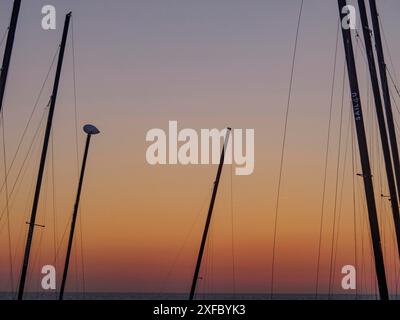 Silhouetten von Segelbooten vor einem farbenfrohen Sonnenuntergang Himmel und Meer, de Haan, Flandern, Belgien Stockfoto