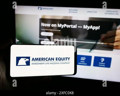 Person mit Smartphone und Logo der American Equity Investment Life Holding Company vor der Website. Schwerpunkt auf dem Display des Telefons. Stockfoto