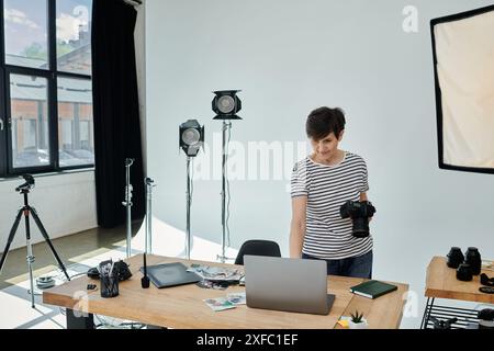 Eine Frau mittleren Alters steht selbstbewusst und arbeitet in modernen Studios an einem Laptop. Stockfoto