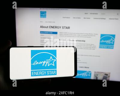 Person, die ein Smartphone mit dem Logo des US-Energieeffizienzprogramms Energy Star vor der Website hält. Schwerpunkt auf dem Display des Telefons. Stockfoto