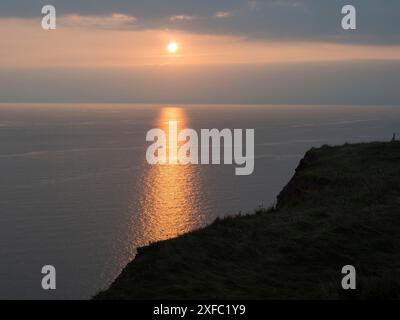 Die untergehende Sonne wirft einen goldenen Lichtstreifen auf das ruhige Meer in der Abenddämmerung, helgoland, Nordsee, deutschland Stockfoto