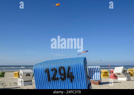 Bunte Liegen stehen am Strand unter blauem Himmel mit fliegenden Drachen, Langeoog, ostfriesland, deutschland Stockfoto