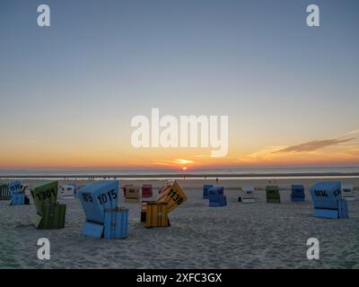 Bunte Liegen am Strand verstreut, Sonnenuntergang über dem Meer im Hintergrund, langeoog, ostfriesland, deutschland Stockfoto