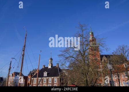 Historische Gebäude und Türme umgeben von Bäumen und einem Schiffsmast im Freien, leer, Ostfriesland, Deutschland Stockfoto