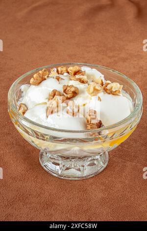 Joghurtdessert mit Honig und Walnüssen in einer Glasschale. Selektiver Fokus mit geringer Schärfentiefe. Stockfoto