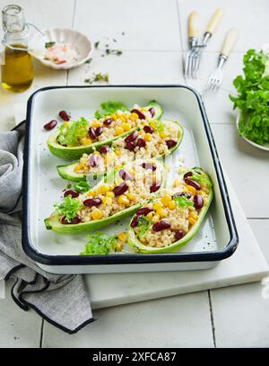 Zucchini gefüllt mit Petitim, roten Bohnen, Mais mit Basilikum und Soße, gebacken auf einem alten, zerrissenen Fliesenhintergrund. Draufsicht. Stockfoto