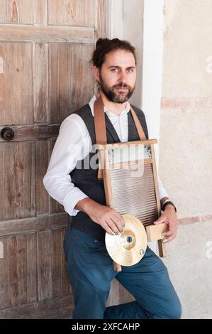 Nahaufnahme eines Mannes, der ein Jazzinstrument auf einem Waschbrett auf der Straße spielt. Das Instrument ist zu sehen, zusammen mit der Zimbel, dem Holz und den Zimbeln Witz Stockfoto