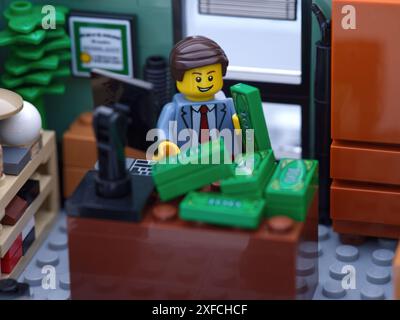 Tambow, Russische Föderation - 2. Juli 2024 Eine Lego-Geschäftsmann-Minifigur, die in einem Büro sitzt und Geld zählt. Nahaufnahme. Stockfoto