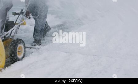 Ein Mann entfernt Schnee mit einem Schneepflug. Schwierige Witterungsbedingungen. Stockfoto