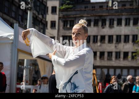 Eine ruhige Tai-Chi-Meisterin in einem fließenden weißen Anzug tritt anmutig auf einer belebten Straße auf, ihre fließenden Bewegungen stehen im Kontrast zur lebendigen städtischen Kulisse Stockfoto