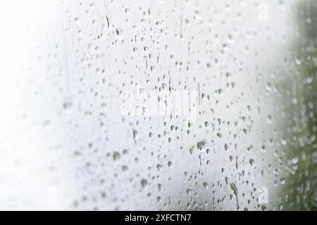 Regentropfen auf einem hellen Fensterglas an einem regnerischen Tag, Wetter- und Wetterkonzept, Kopierraum, ausgewählter Fokus mit sehr geringer Schärfentiefe Stockfoto