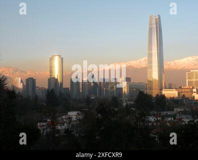 Sonnenuntergangslichter über Geschäftsgebäuden mit verschneiten Bergketten im Hintergrund und Luftverschmutzung Stockfoto