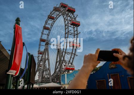 Wien, Österreich, 18. August 2022. Aufnahme des großen alten Riesenrads im Vergnügungspark der Stadt, dem prater. Ein Mobiltelefon wird angehoben, um einen aufzunehmen Stockfoto