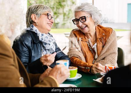 Ältere Frauen lachen beim Frühstück mit einer Gruppe von Freunden Stockfoto