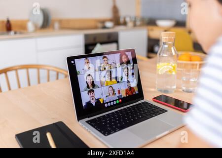 Rückansicht einer jungen Frau, die mit multirassischen Kollegen im Videogespräch spricht Stockfoto