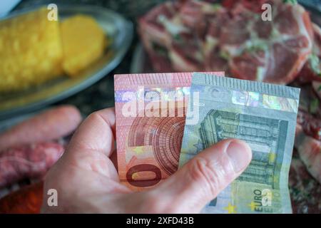 Euro-Scheine in meiner linken Hand. Konzept, die steigenden Preise für Fleisch und Obst Stockfoto