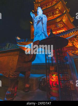 Jakarta, Indonesien - 11. Mai 2024. Ein Foto einer hell erleuchteten Statue der Guanyin-Göttin, die in warmes Licht getaucht ist und vor einem traditionellen Pago steht Stockfoto