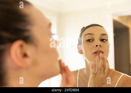 Make-up auftragen, junge Frau, die im Badezimmerspiegel reflektiert Stockfoto