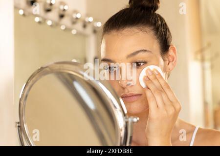 Make-up auftragen, junge Frau mit Wattepad vor dem Spiegel Stockfoto