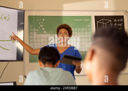 Unterricht in der High School, Lehrer mit Tablet und Zeigen auf Whiteboard im Klassenzimmer Stockfoto