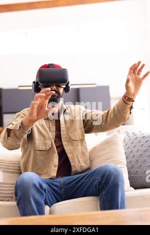 Mit dem VR-Headset, einem Mann, der auf dem Sofa sitzt und die virtuelle Realität zu Hause erlebt, Kopierraum Stockfoto