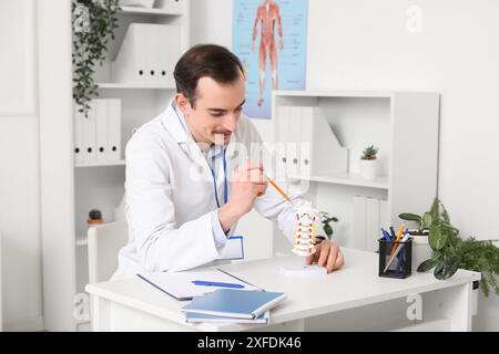 Männlicher Arzt mit Wirbelsäulenmodell in der Klinik Stockfoto