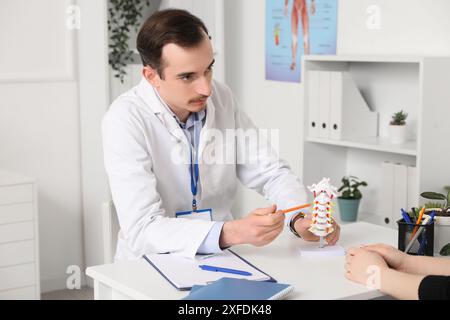 Arzt erklärt Wirbelsäulenanatomie mit Wirbelsäulenmodell dem Patienten in der Klinik Stockfoto