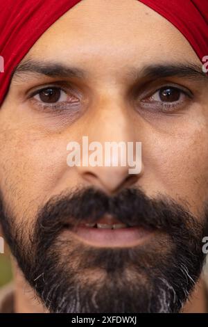 Nahaufnahme eines Indianers mit Bart und rotem Turban, der in die Kamera schaut Stockfoto