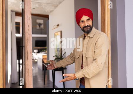 Einladende Gäste, Mann in rotem Turban, einladend in moderne Inneneinrichtung Stockfoto