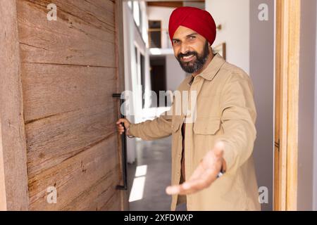 Begrüßungsgast, Mann im Turban, der Tür öffnet und Gesten im Haus macht, Kopierraum Stockfoto