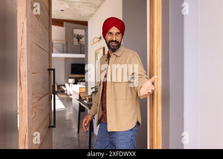 Wir begrüßen Gäste, Mann im Turban, der die Tür öffnet und einladend im Haus ist Stockfoto