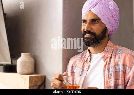 Mit einer Tasse Tee, Mann im Turban, der sich zu Hause entspannt, Kopierraum Stockfoto