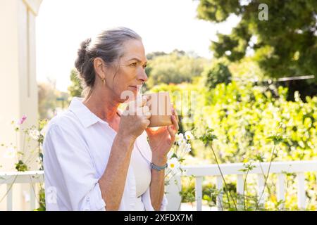 Reife Frau trinkt Kaffee auf dem Balkon, genießt friedlichen Morgen draußen, Kopierraum Stockfoto