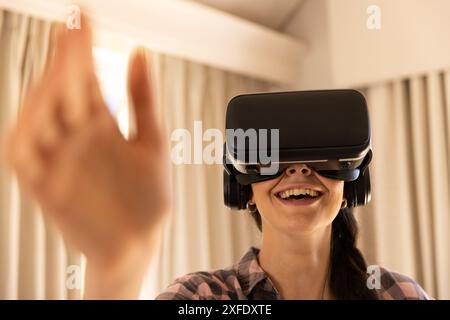 Mit dem VR-Headset lächelt die Frau und interagiert mit der virtuellen Umgebung Stockfoto