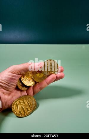 Hand hält verschiedene Kryptowährungen am Tisch im Studio Stockfoto