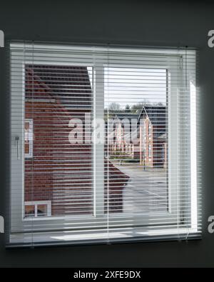 Wohnraum. Blick vom Fenster durch die Jalousien auf die Straße und die roten Backsteinhäuser Stockfoto